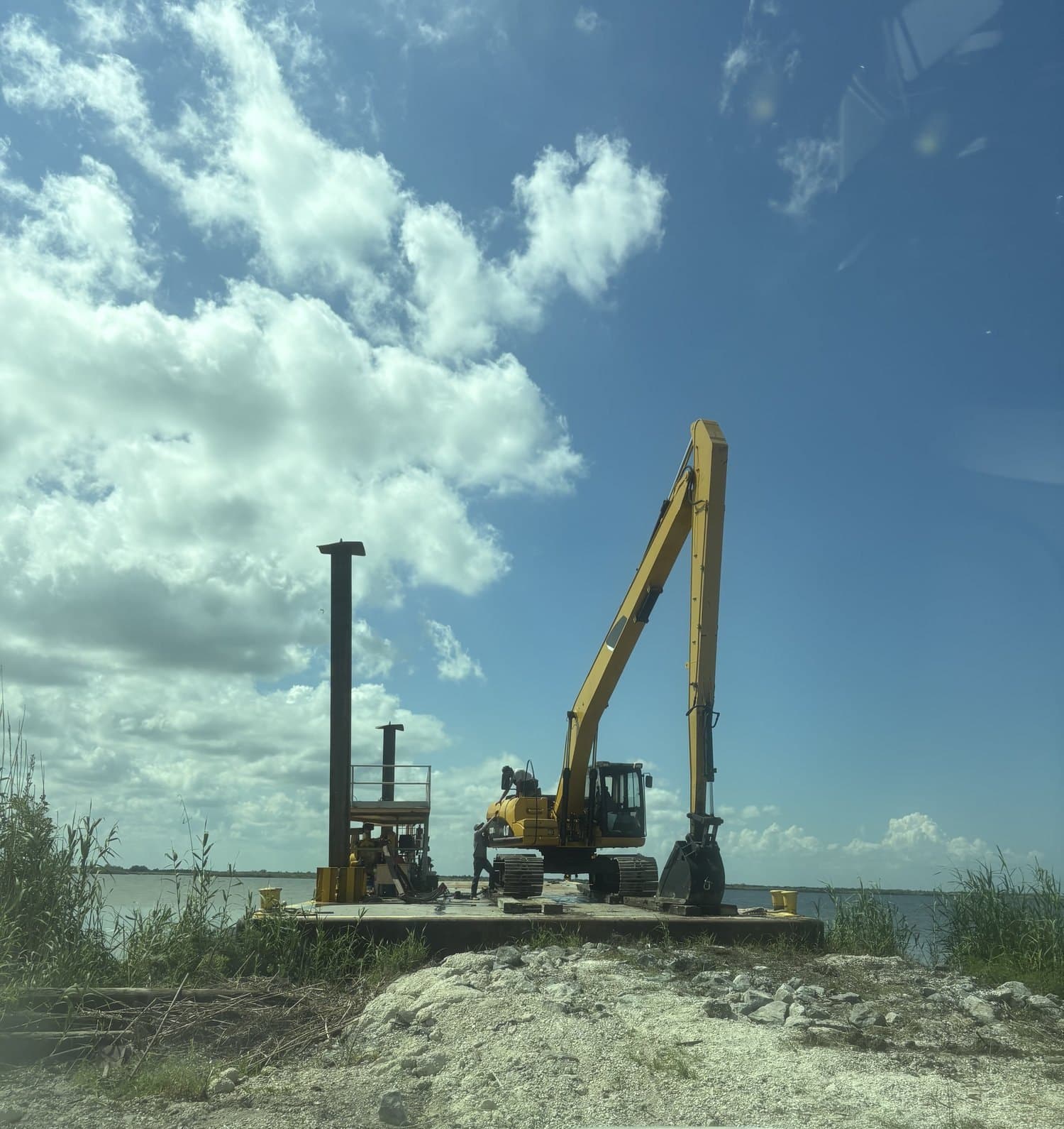 Long-reach excavator and pile-driving rig working from a spud barge in South Louisiana
